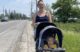 A woman poses for a photo with her young son in a stroller along the side of Route 1.
