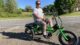 David Ginn poses for a photo while sitting on his large green bike.