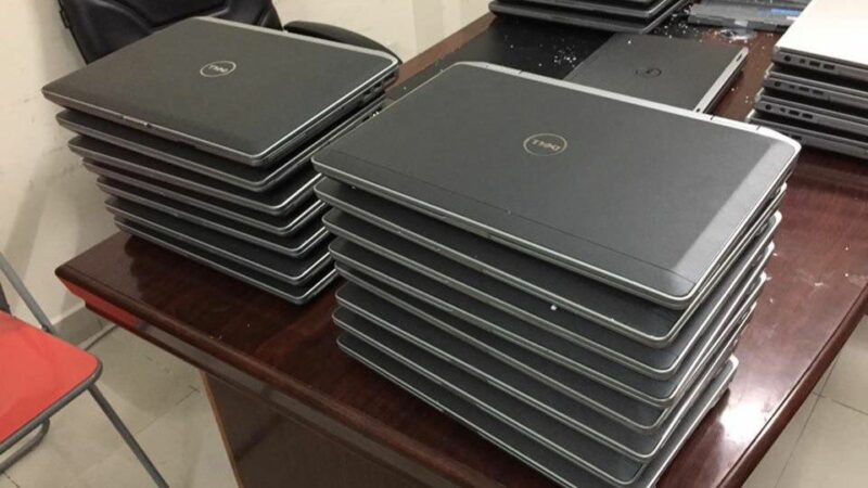 A stack of closed laptops on a desk.