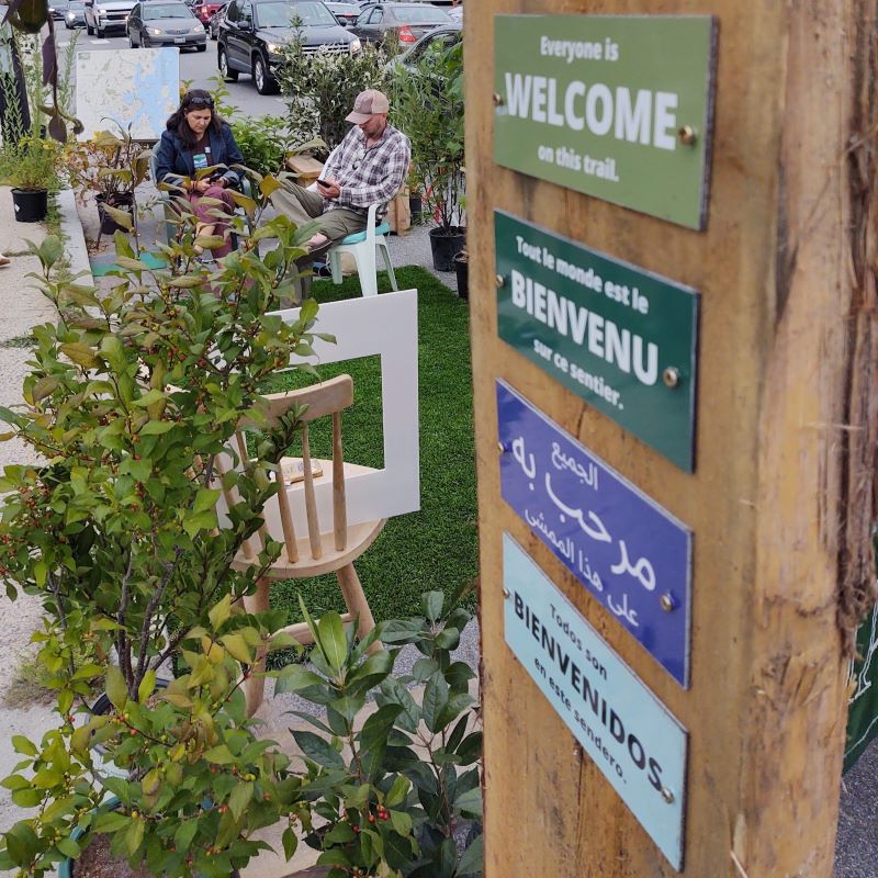 Four signs, each in a different language, attached to a post at the head of a trail in Portland. Each, in a different language, reads "Everyone is welcome on this trail."