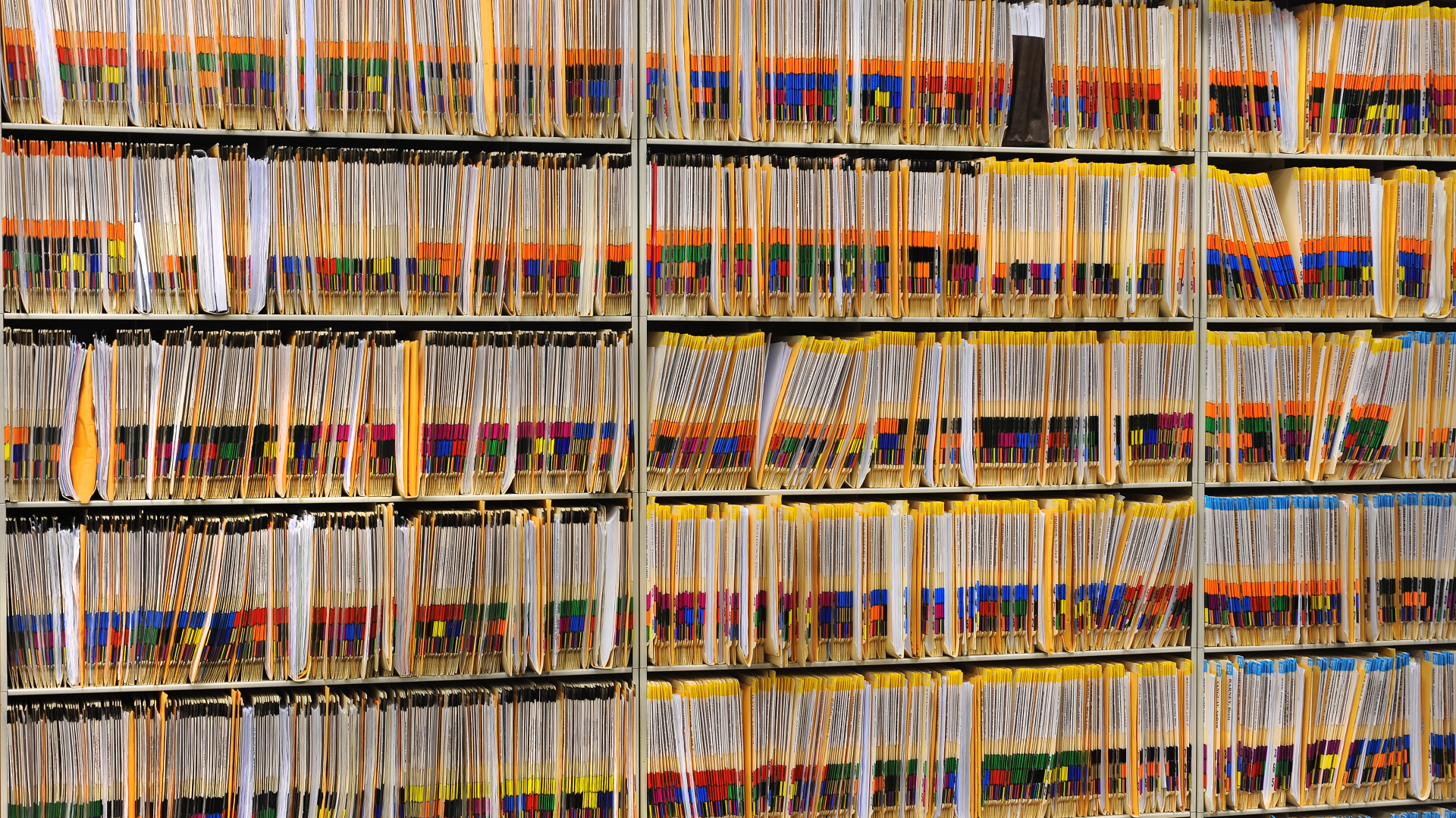 Multiple shelves are overflowing with probate court case files inside a courthouse office.