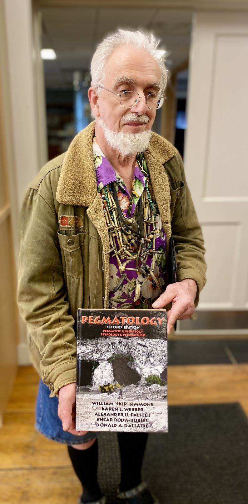 Al Falster poses for a photo while showing off the textbook he authored.