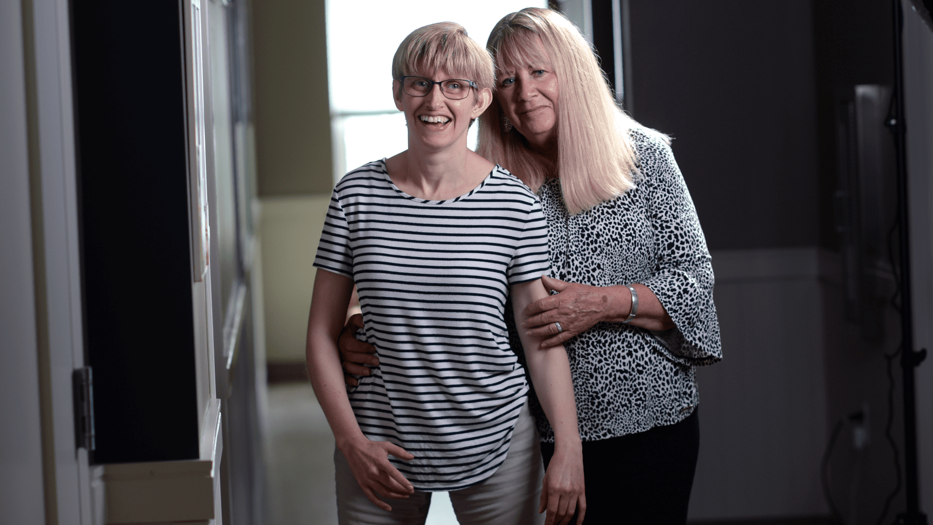 Kate Riordan and her mother Debbie Dionne pose for a photo in the hallway of a home.