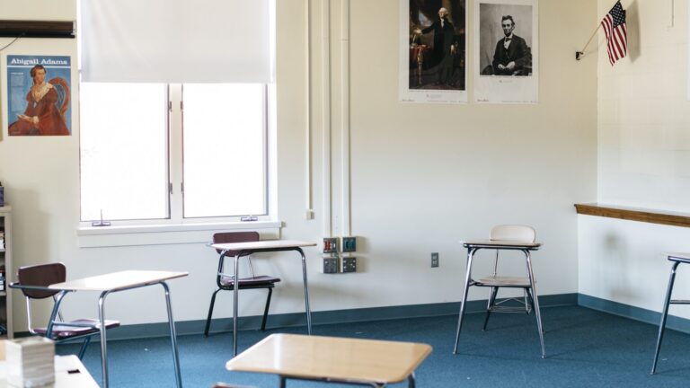 An empty classroom with four desks for students spread out.