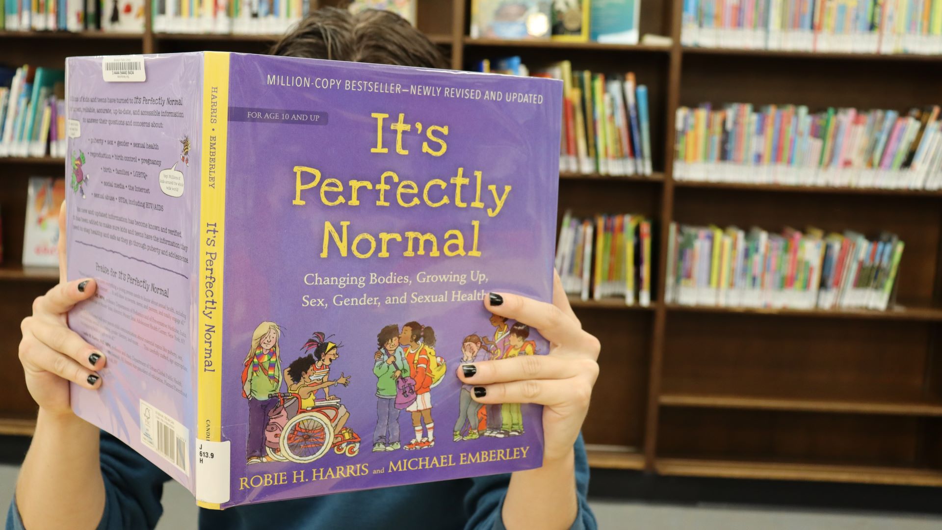An individual reading the book It's Perfectly Normal.