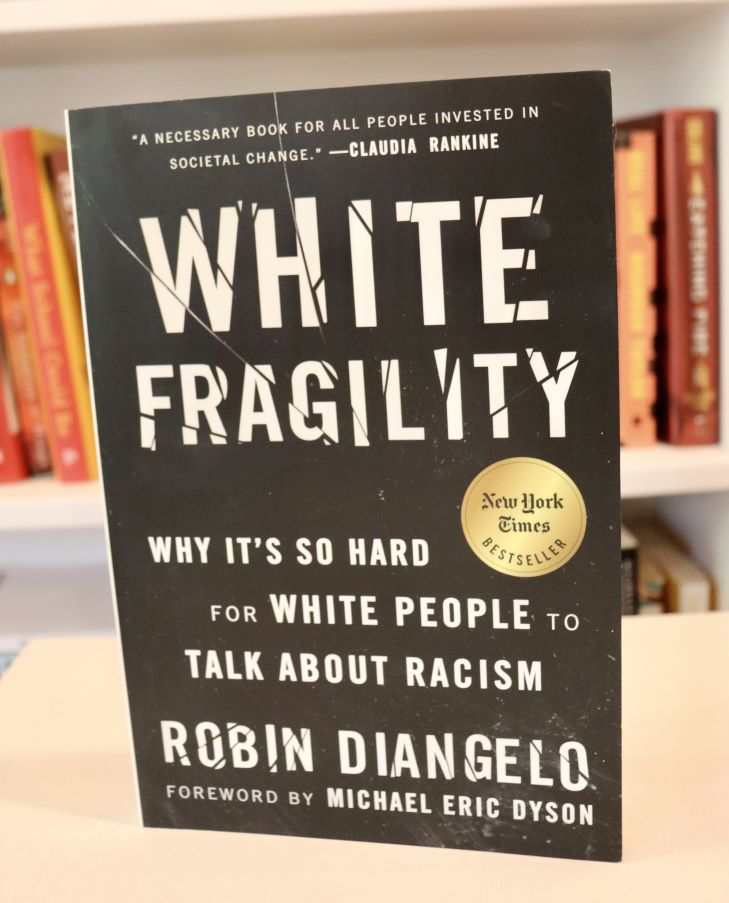 A copy of the book White Fragility stands upright on a table.
