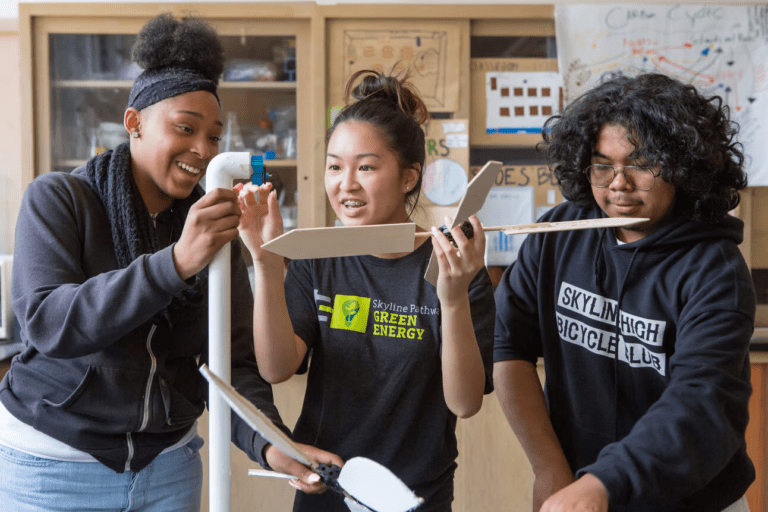 Three students assembling a model wind turbine.