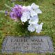 The burial site of Laurie Wall surrounded in part by flowers.