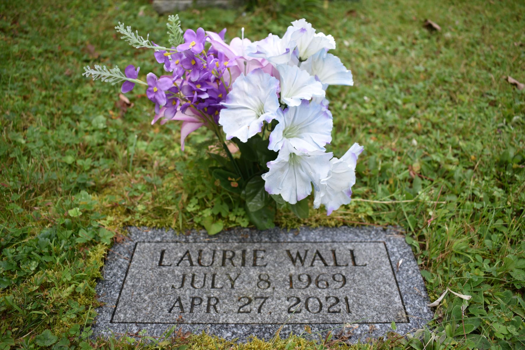 The burial site of Laurie Wall surrounded in part by flowers.