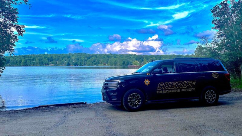 A Piscataquis County sheriff car parked alongside a lake.