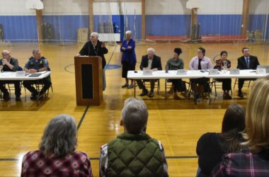 A view of the speakers' area, including of a woman speaking at the podium, during the meeting.