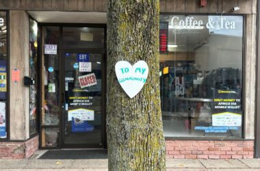 A white paper heart that says to my community is stapled to a tree.