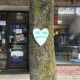 A white paper heart that says to my community is stapled to a tree.
