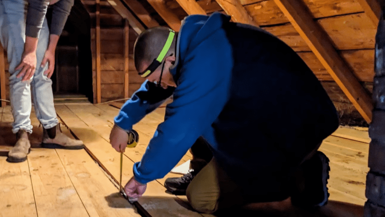 An energy auditor using a measuring tape. 