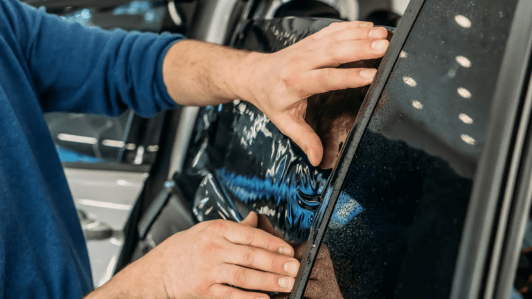 Hands place tinting on a window of a car.