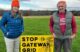 Holly Noyes and Chuck Noyes pose for a photo next to a yellow stop gateway grid yard sign.