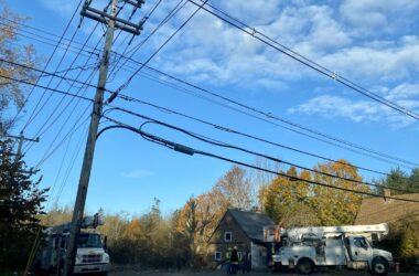 Power trucks are seen parked underneath electric lines.
