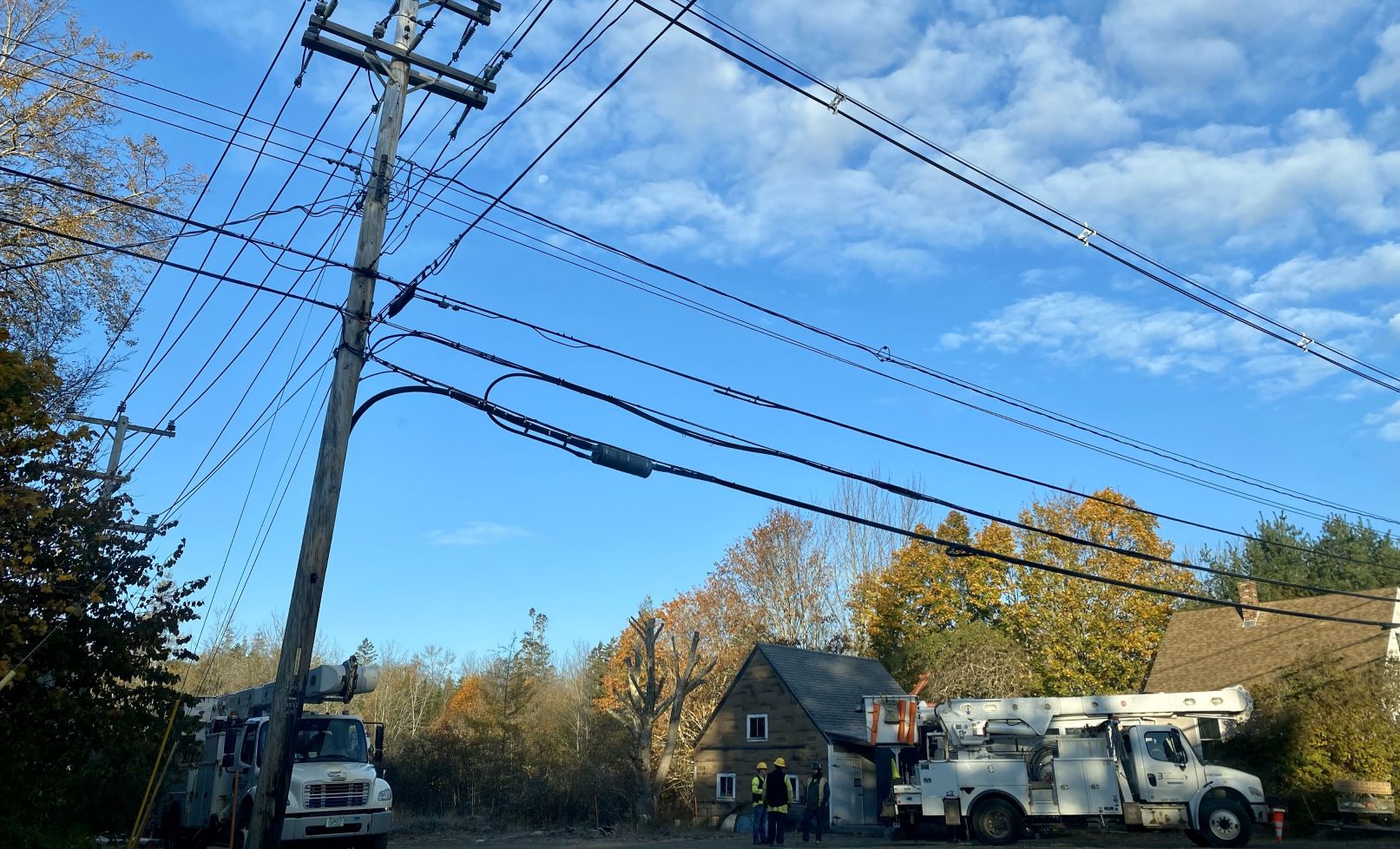 Power trucks are seen parked underneath electric lines. 
