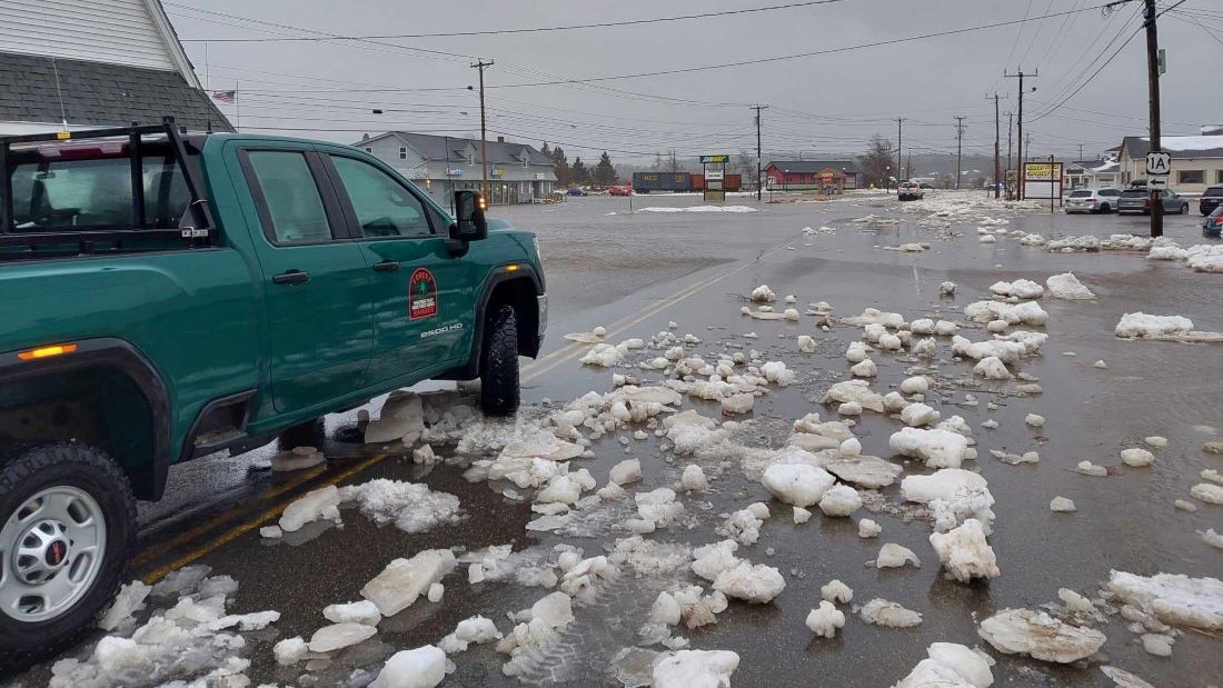 A green forest ranger truck surveys the flooding on a Machias street.