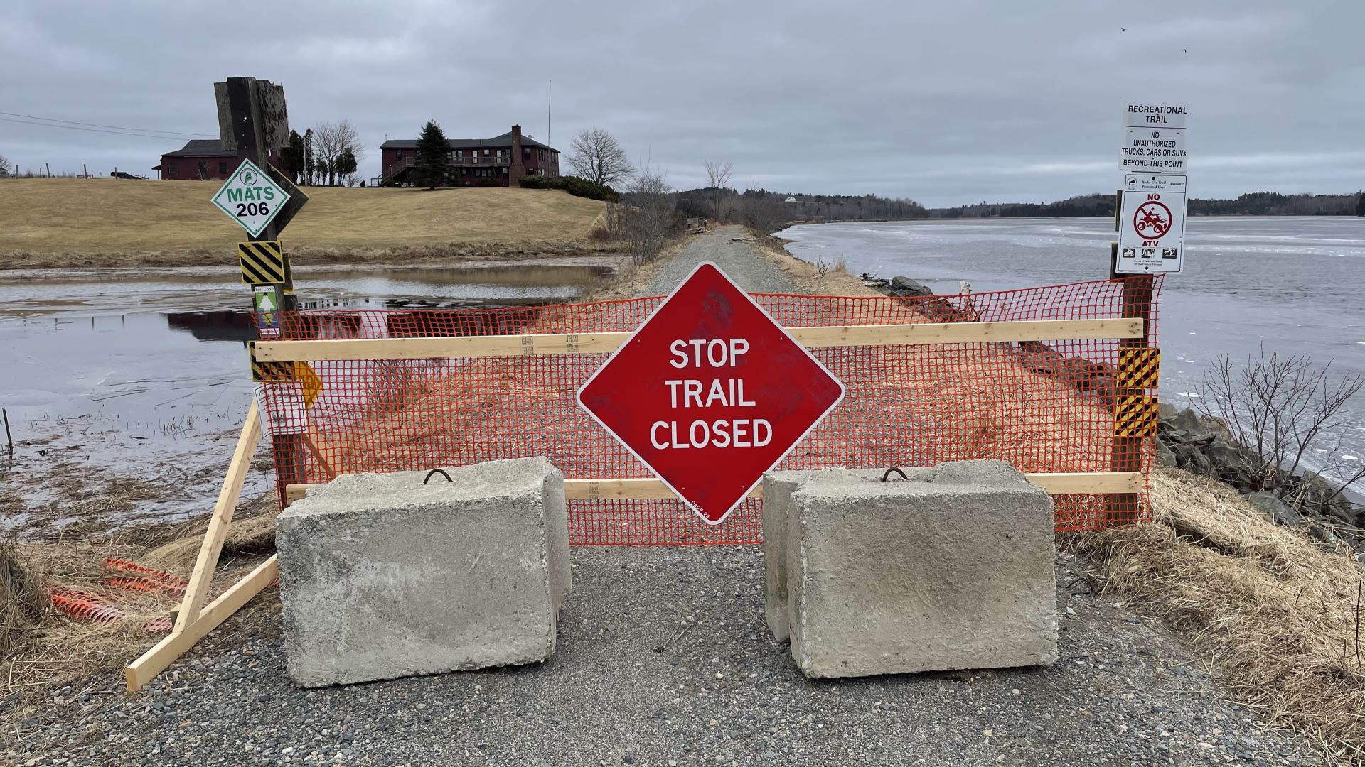 The entrance to the trail is blocked by a makeshift barrier.