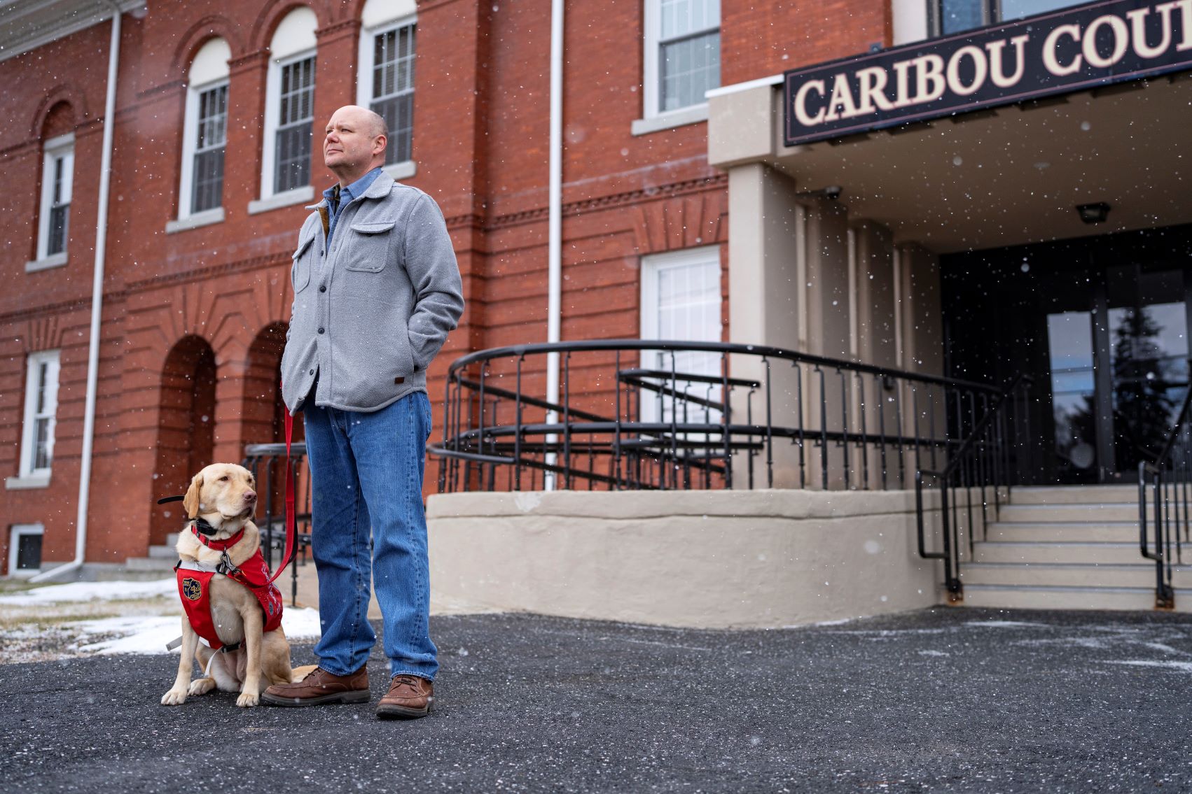 Todd Collins poses for a photo, while holding the leash to his dog, outside a courthouse.