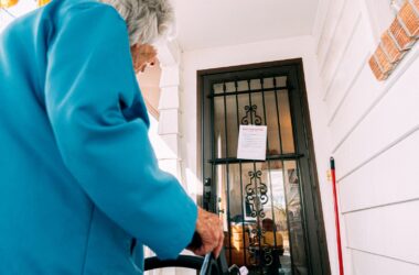 An elderly woman looks at an eviction notice on her door.