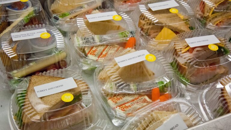 Rows of deli sandwiches packed in to-go containers.