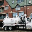 A water pump truck outside of a condo building.