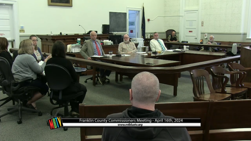 A group of county officials gathered around a table during a commissioner meeting.