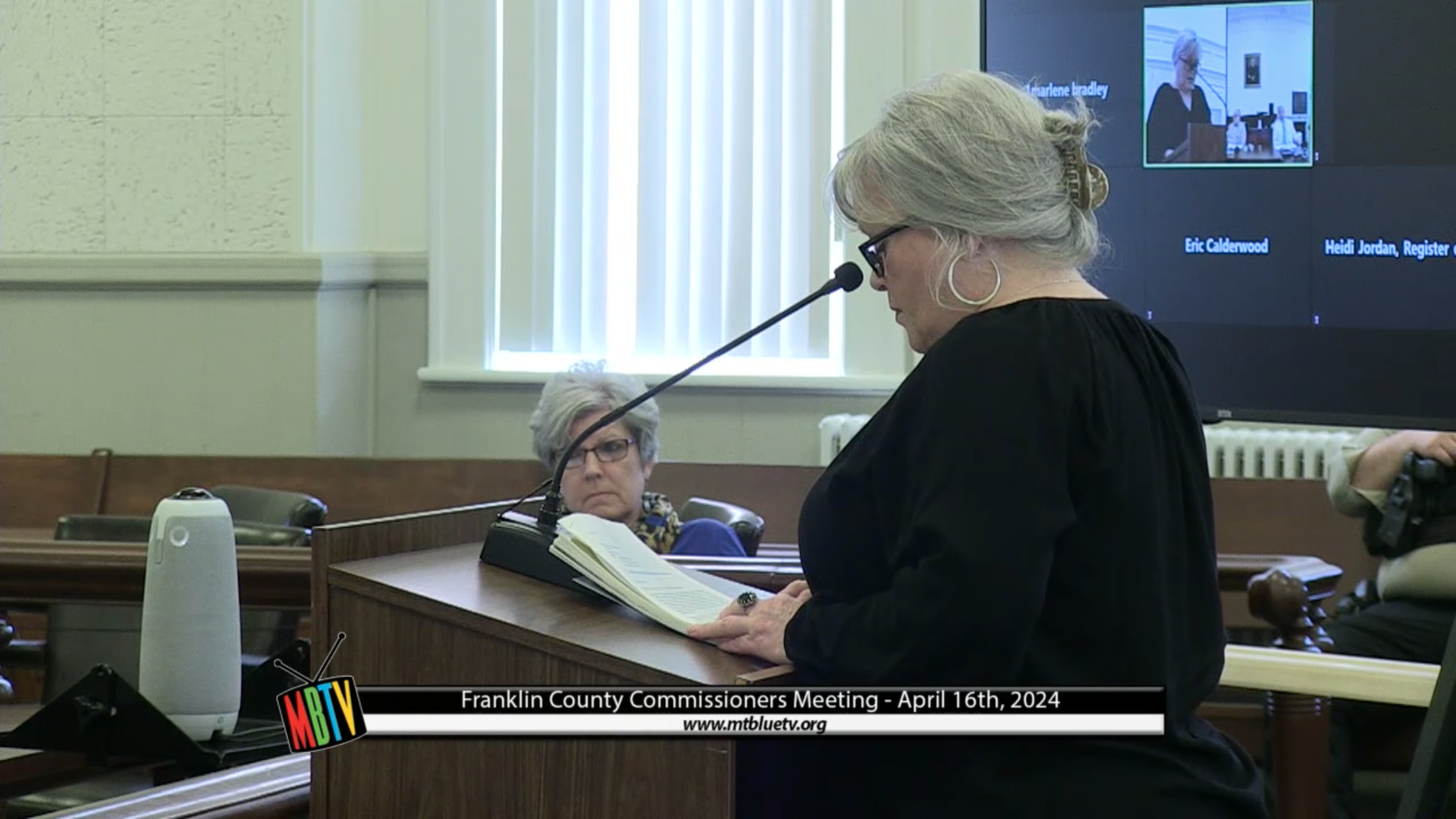 Bonita Tompkins speaks while standing at a podium during a commission meeting.