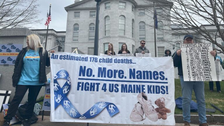 People attending the rally hold a large banner that reads "An estimated 178 child deaths. No more names. Fight for us Maine kids."