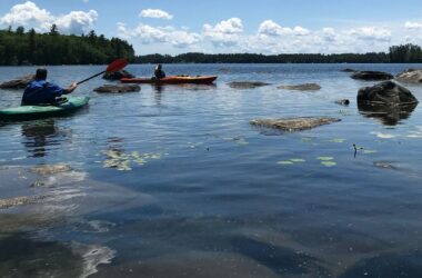 Two kayakers on a lake in Maine.