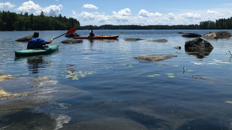 Two kayakers on a lake in Maine.