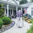 A man uses a walker to get up the walkway to his home's front door.