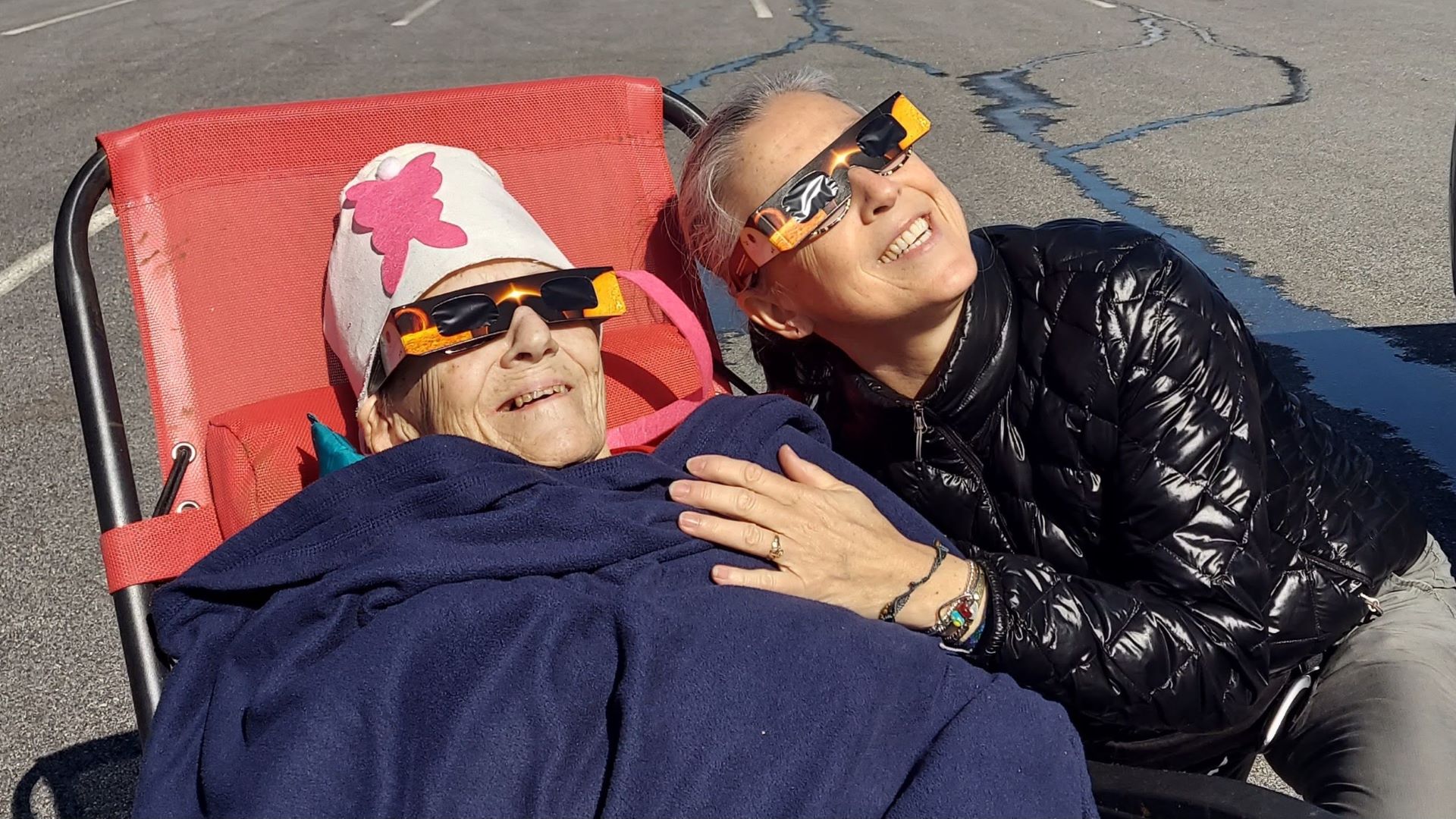 Pauline Kane and Ann Marie Kane sit in a parking lot while observing the solar eclipse.
