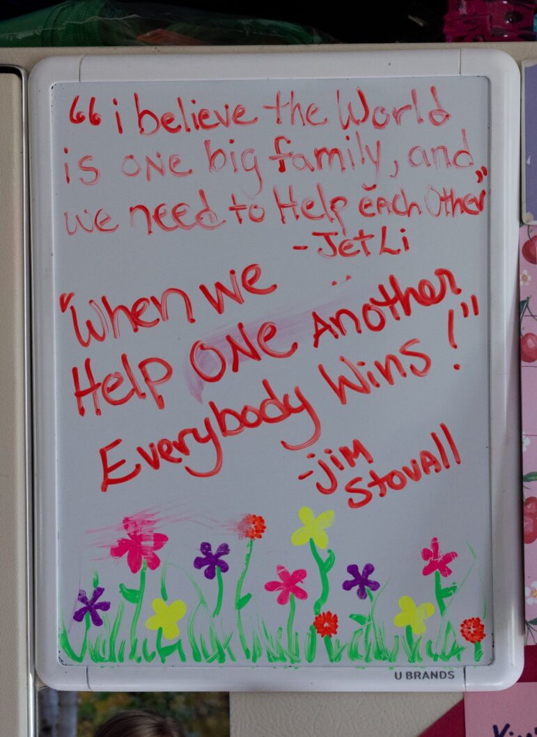 Notes of encouragement left on a white board. One note reads "I believe the world is one big family and we need to help each other." Another note reads "when we help one another everybody wins."