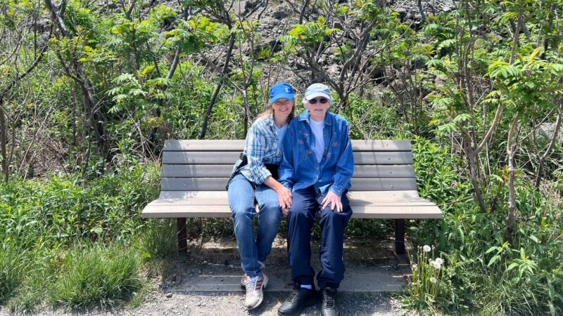 Two women sitting on a park bench.