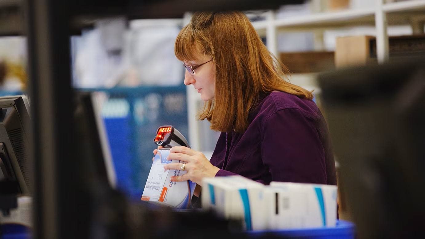 A mail service pharmacist scans an item.