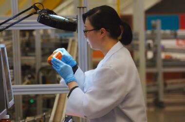 A pharmacist filling an orange pill bottle.