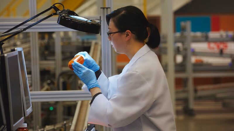 A pharmacist filling an orange pill bottle.