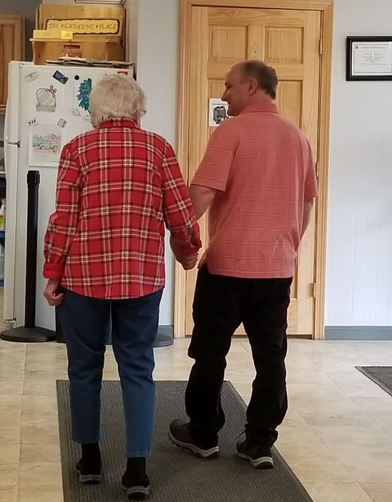 An aide and a patient walking through a building.