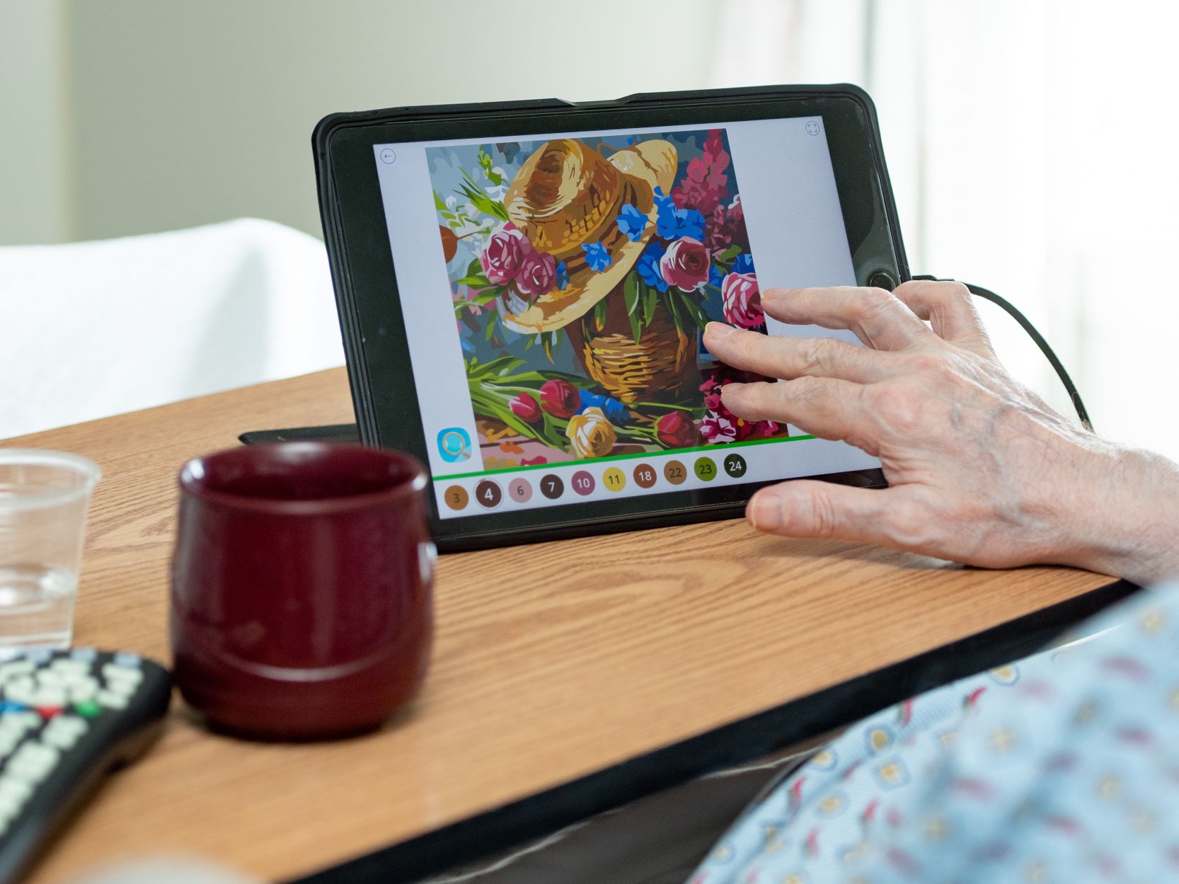 A patient's hand touches a tablet on a table.