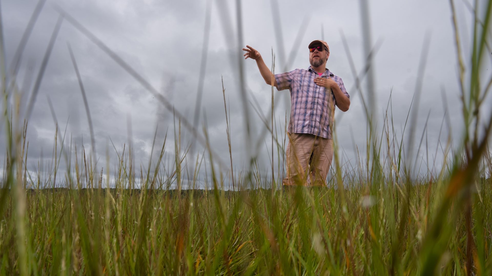 Jacob Aman stands amid marsh grass during a conversation.