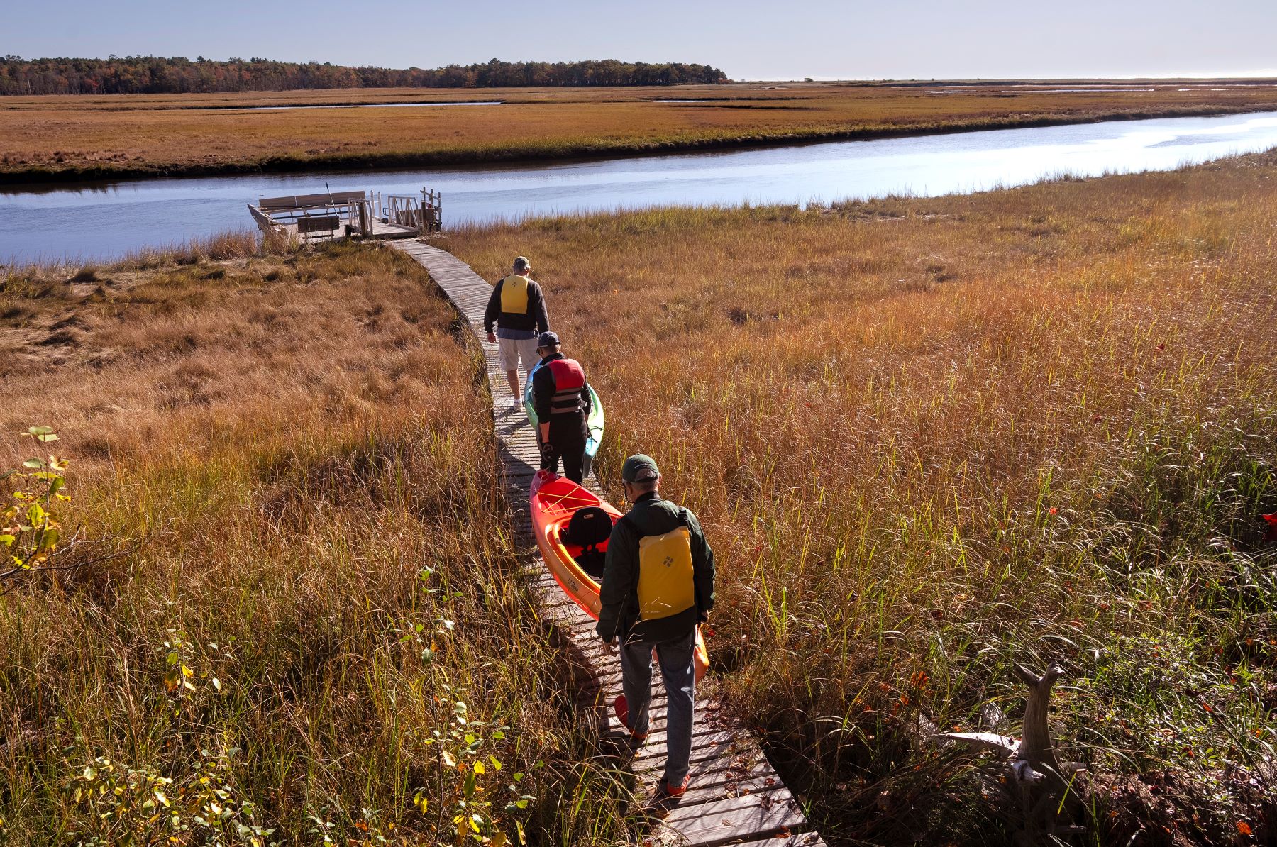 A group of men carrying a kayak while walking down a boardwalk.