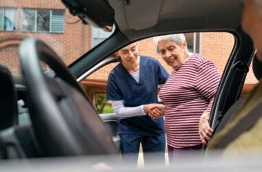 A health aide assists a woman as she gets inside a personal medical transport vehicle.