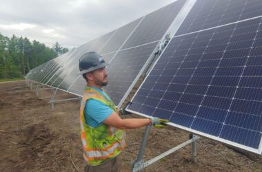 A man installs solar panels in a field.