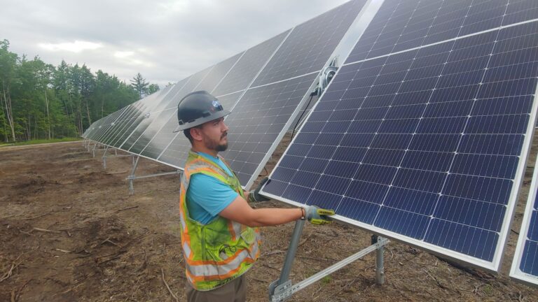 A man installs solar panels in a field.