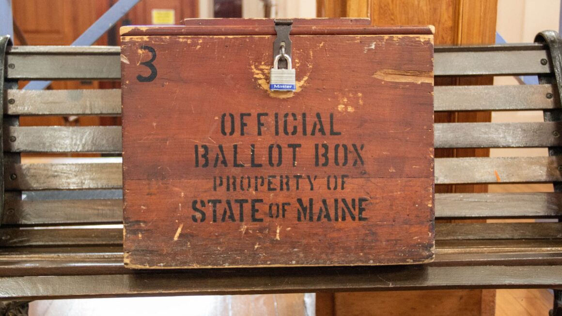 A locked wooden box stamped with the phrase "Official ballot box property state of Maine"