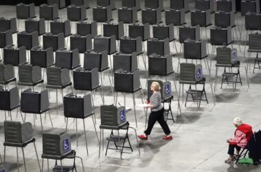 A woman walks through a row of empty voting stations.