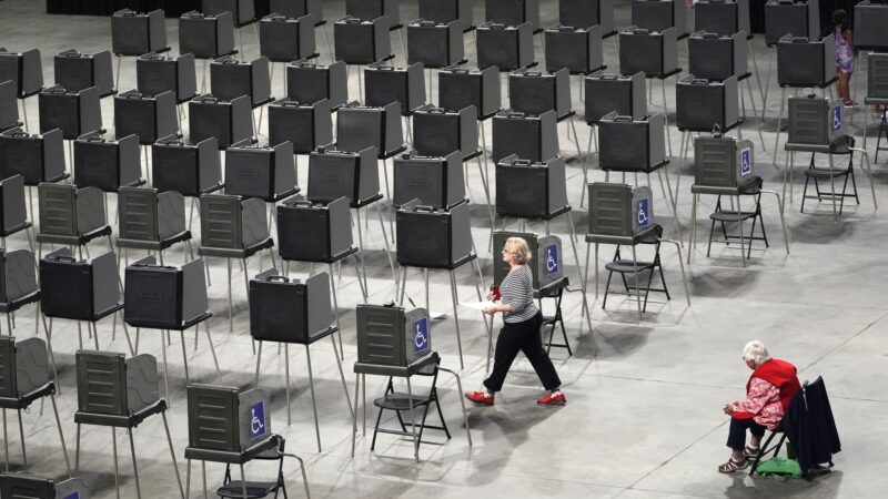 A woman walks through a row of empty voting stations.